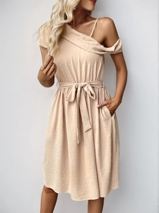 Detailed view of the textured Swiss dot fabric and waist tie on this beige summer dress
