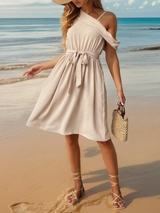 Off-shoulder beige vacation dress with swiss dots and drawstring waist on a beach
