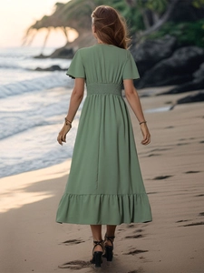 Detail of smocked waist and ruffled hem on a green summer maxi dress at the beach