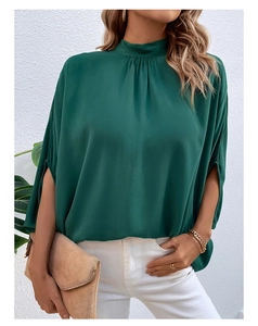 Detail of elegant dark green high-neck blouse featuring pleated collar and split batwing sleeves