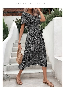 Détail d'une robe noire à fleurs avec col en V et volants sur le bas de la jupe