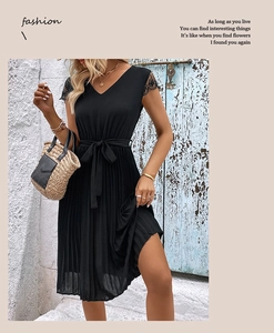 Detail of black V-neck pleated dress featuring floral lace sleeves and waist bow tie