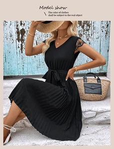 Detail shot of black V-neck summer dress with lace sleeves and pleated skirt finish