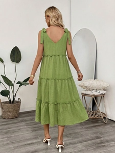 Detail of green cotton linen dress featuring tiered skirt and adjustable bow straps