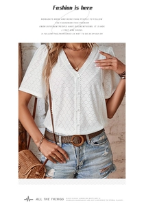 Close-up of white eyelet lace V-neck blouse with delicate button details and texture
