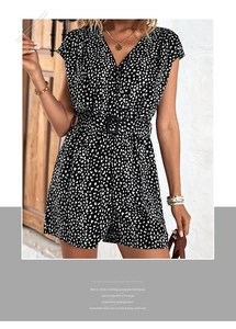 Detail of V-neck floral romper featuring a black fabric with white print and buckled waist belt