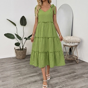 Detail of green cotton linen dress featuring bow straps and a tiered ruffle skirt design