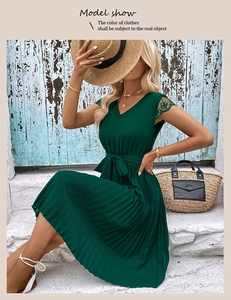 Detail of dark green V-neck pleated dress featuring delicate lace trim and waist tie