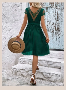 Detail of dark green backless summer dress with lace embroidery and pleated skirt texture
