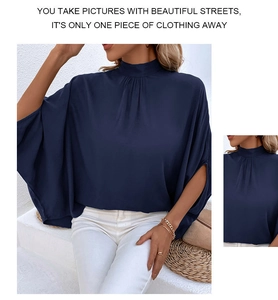 Detail of navy blue half-turtleneck top with elegant batwing sleeves and draped fabric