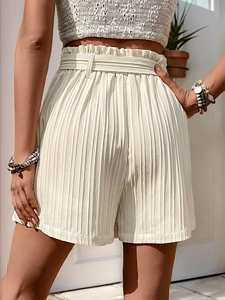 Detail of high waisted pleated shorts with paperbag waist and matching tie belt