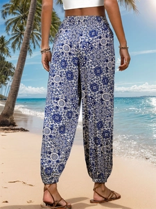 Rear view of high waist boho pants featuring blue and white mandala print on a beach
