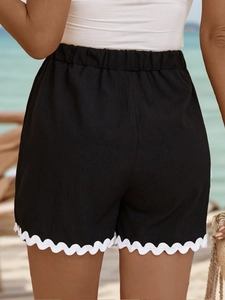 Rear view of black high waisted shorts featuring white wavy scalloped lace trim details