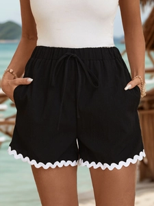 Close-up of black drawstring shorts with white scalloped lace trim and elastic waistband