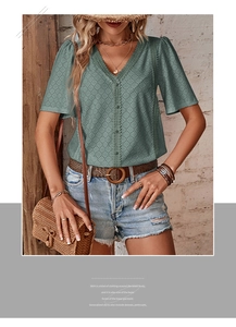Close-up of sage green eyelet embroidery fabric with V-neck and delicate lace edges
