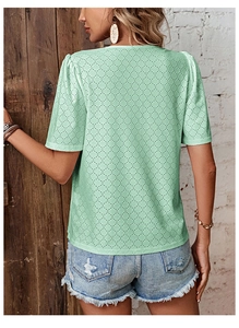 Detail of mint green eyelet lace summer shirt featuring delicate hollowed-out fabric patterns