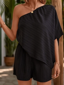 Close-up of black one-shoulder jumpsuit with textured pleated fabric in outdoor setting