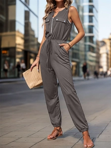 Detail of grey sleeveless jumpsuit featuring front zipper V-neck and drawstring waist tie