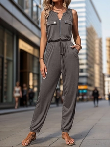 Detail of grey sleeveless jumpsuit featuring front zipper and drawstring waist on urban street