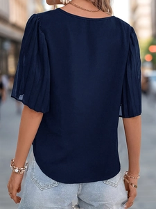 Rear view of navy blue blouse featuring pleated puff sleeves and light denim shorts