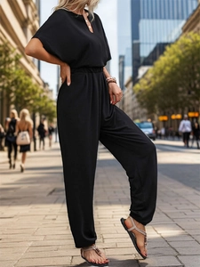Detail view of women's black minimalist jumpsuit with V-neckline and elastic waist design