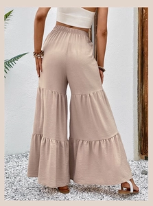 Detail view of the high waist elastic band and three-tier ruffle hem on beige flared pants