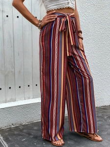 Close-up of bohemian high-waisted wide-leg pants with geometric stripes and bow belt detail