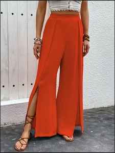 Detail of red high-waisted wide-leg trousers with front slits and pleated texture fabric