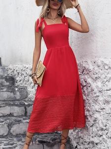 Close-up of red sleeveless dress featuring shoulder bow ties and pleated hem detail