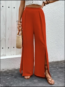 Detail of red high-waisted wide-leg trousers featuring side slits and seersucker texture