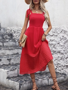 Detail of red sleeveless midi dress with tie-up straps and pleated hem for summer beach