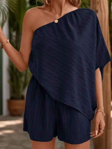 Detail of dark blue one-shoulder jumpsuit featuring textured plissé pleated fabric finish