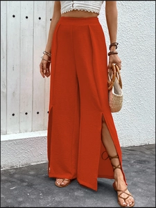 Detail shot of the red high-waist wide-leg pants featuring high side slits and textured fabric