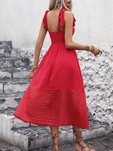 Detail of red sleeveless summer dress featuring adjustable tie straps and pleated hemline