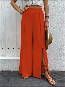 Detail of high-waisted red wide-leg trousers featuring stylish side slits and pleated waist