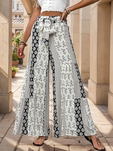 Detail of high waisted bohemian wide leg pants with floral print and tiered smocked design