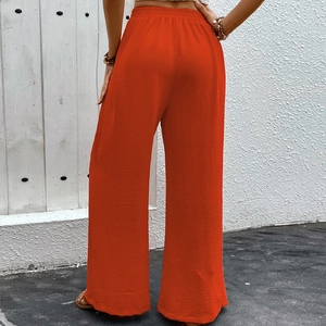 Women's orange high-waist wide-leg pants in textured fabric showing the back view
