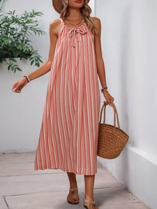 Détail d'une robe dos nu à rayures roses et blanches avec nœud et accessoires de vacances