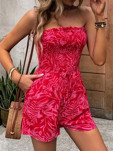 Detail of tropical print romper featuring smocked waist and strapless ruffled neckline
