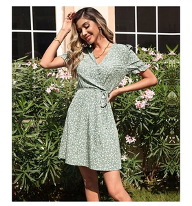 Detailed view of the V-neck and white floral print on a light green summer wrap dress