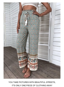 Détail d'un pantalon large taille haute avec imprimé cachemire et cordons à glands