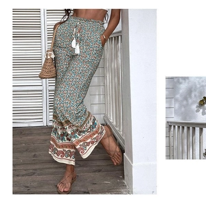 Détail du pantalon bohème à jambes larges avec imprimé fleuri et cordon à pompons blancs