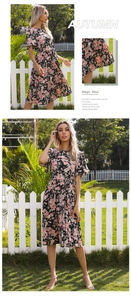 Detail view of a black floral midi dress with ruffle sleeves and a waist tie in a garden