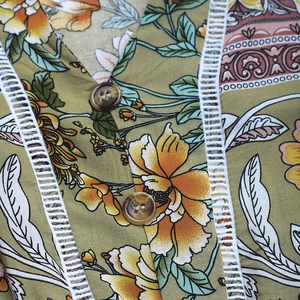 Détail de robe bohème à fleurs avec décolleté en V, bordures en dentelle et boutons