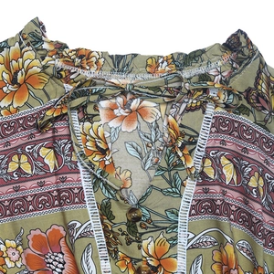 Détail de robe fleurie bohème avec encolure à volants, cordon de serrage et dentelle