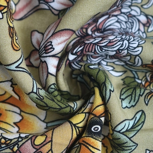 Gros plan sur un tissu floral vert olive avec des fleurs roses et orange et une texture douce