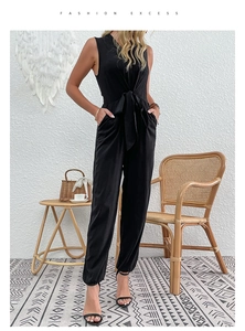 Detail showing the adjustable self-tie bow and functional side pockets of the black jumpsuit