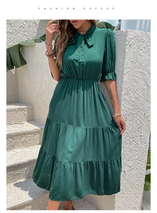 Detail of dark green dress showing tie-knot neckline and tiered cake skirt layers