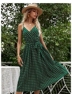 Close-up of dark green polka dot midi dress showing pleated skirt and waist tie detail