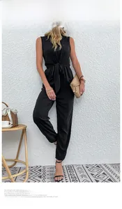Detail of black V-neck jumpsuit featuring a waist tie bow and cinched ankle cuffs